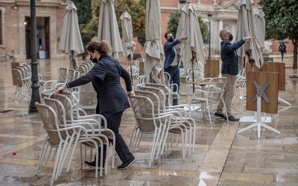 Camareros retiran la terraza de un bar. Pandemia.