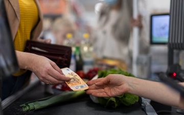 Mujer pagando en un supermercado. Cadenas de distribución. Inflación. (Copyright: HalfPoint)